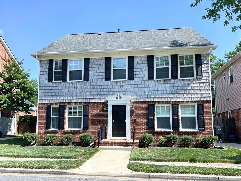 The same house with light gray shingle-style siding on the whole second floor and the red brick kept on the first floor