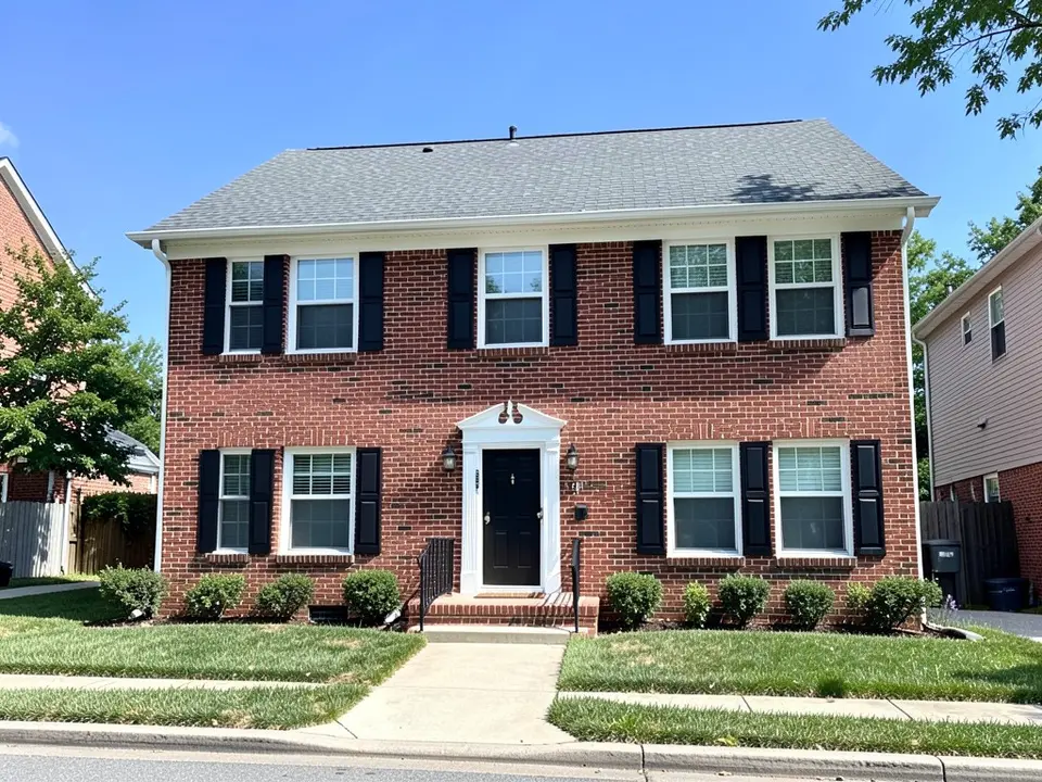 AI-drawn generic stand-in of a two-story colonial-style house with red brick on both floors, white window trim, black shutters, a black front door under a white pediment and a gray shingle roof
