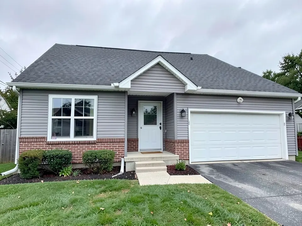 The same house with a red brick veneer base along the bottom of the front walls and the entry; gray siding above, window, door, garage door and roof kept