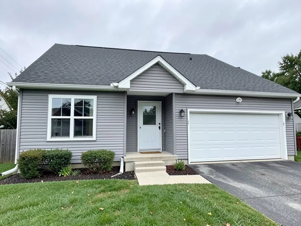 AI-drawn generic stand-in of a one-story house with gray horizontal vinyl siding, a white-trimmed front window, a white front door with concrete steps, a white two-car garage door and a dark gray shingle roof
