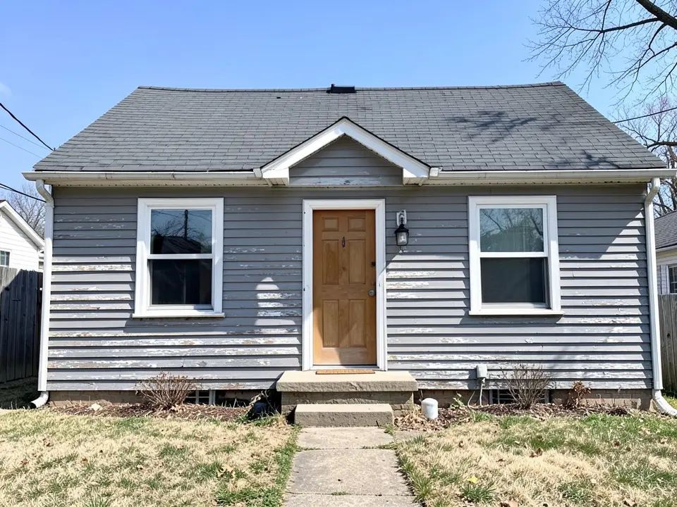AI-drawn generic stand-in of a small cottage with weathered gray painted wood lap siding that is peeling in patches, white trim, a wood front door and a dark gray roof