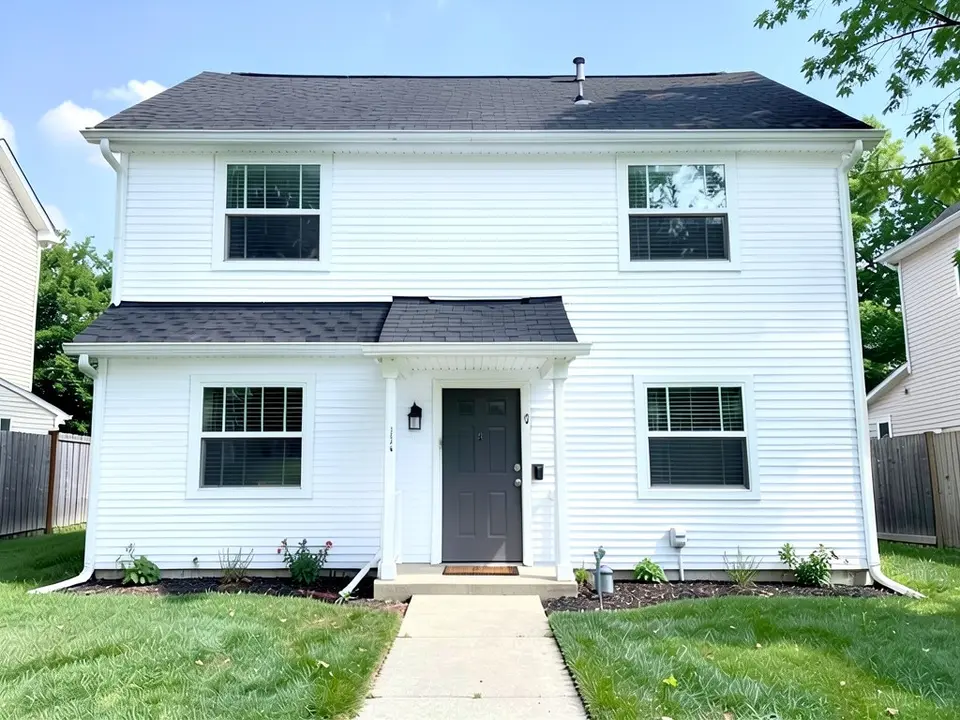 The same house with bright white siding under the same black roof; window trim, door and roof kept