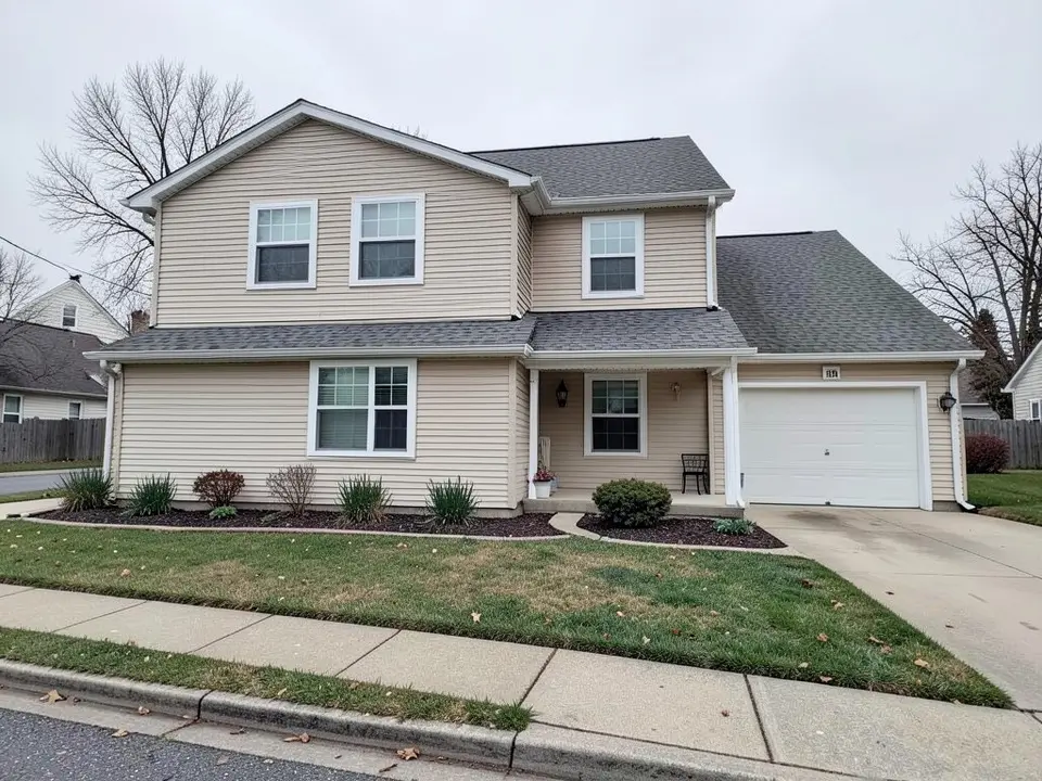 Two-story house with beige horizontal vinyl siding, white trim and a white garage door
