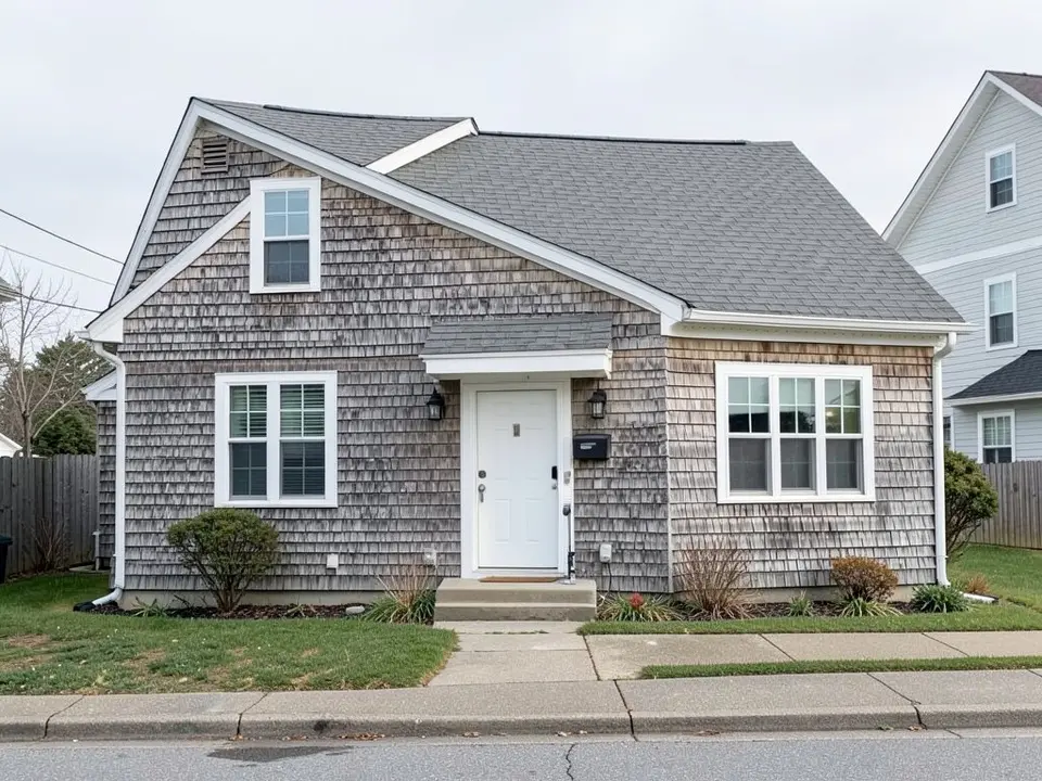 AI-drawn generic stand-in of a coastal cottage with weathered gray shingle walls, white trim, a gray roof and a white front door