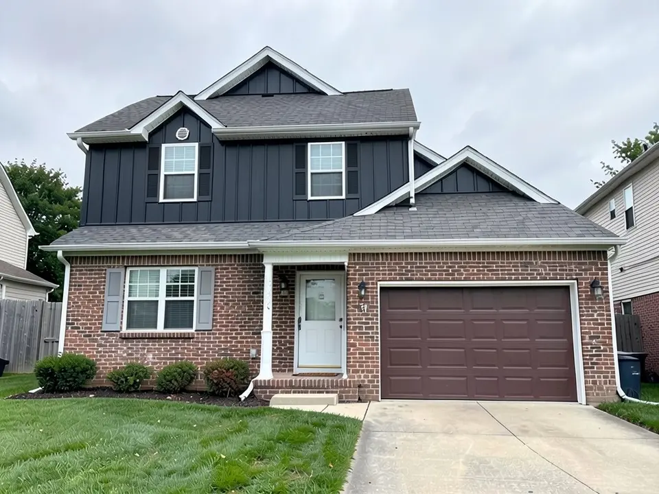The same house with black vertical ribbed panels on the upper floor and both gables, dark shutters on the upper windows, and the red-brown brick, white trim, doors and roof kept