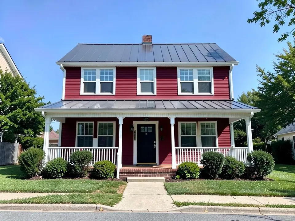 The same farmhouse with deep barn red siding on both floors; white trim, white porch, black door and metal roof kept