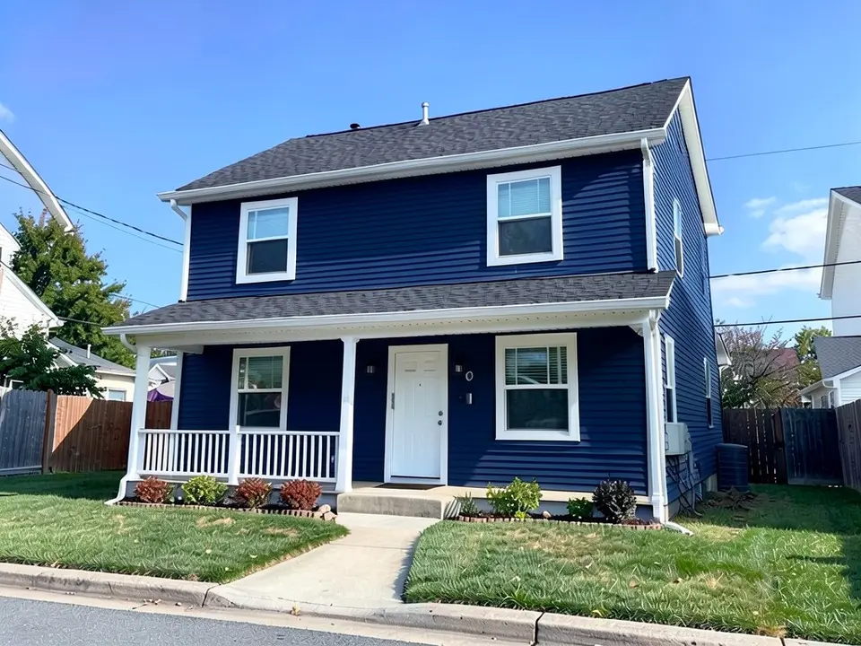 The same house with deep navy siding; white trim, window frames, door and porch posts kept