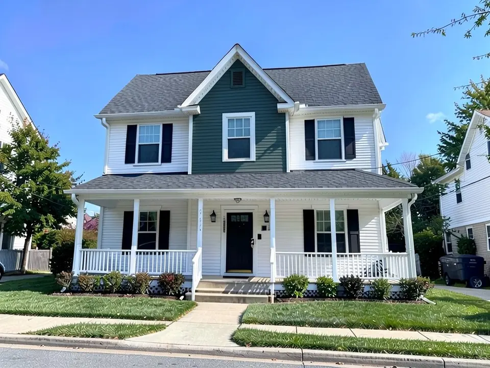 The same house with the front-facing gable siding in dark green-gray and the rest of the siding still white
