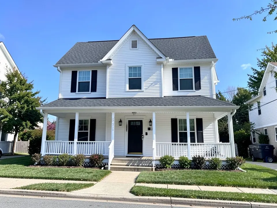 AI-drawn generic stand-in of a two-story white house with white horizontal siding, black shutters, a front-facing gable above the entry and a covered porch with white railing